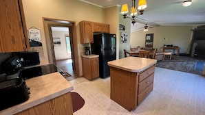 A kitchen with wooden cabinets, a black refrigerator, and a coffee maker.