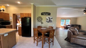 A spacious kitchen with wooden cabinets, a black refrigerator, and a dining area with a table and chairs.