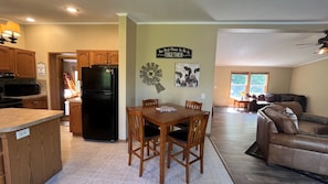 A spacious kitchen with wooden cabinets, a black refrigerator, and a dining area with a table and chairs.