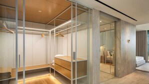 A modern hotel room with a walk-in closet, a wooden vanity, and a seating area with a sofa and a coffee table. - Savoy Monumentalis XI – Luxury with sea view (Funchal)