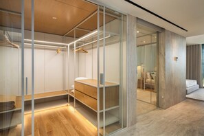 Ein modernes Hotelzimmer mit begehbarem Kleiderschrank, einem Holzbüro und einer Sitzecke mit Sofa und Couchtisch.