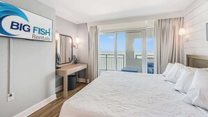 Quarto de hotel com cama, escrivaninha, espelho, janela com cortinas e um aviso para Big Fish Rentals.