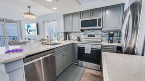 Une cuisine moderne avec des armoires grises, des appareils en acier inoxydable et un grand îlot central.