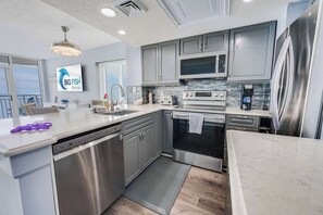 Une cuisine moderne avec des armoires grises, des appareils en acier inoxydable et un grand îlot central.