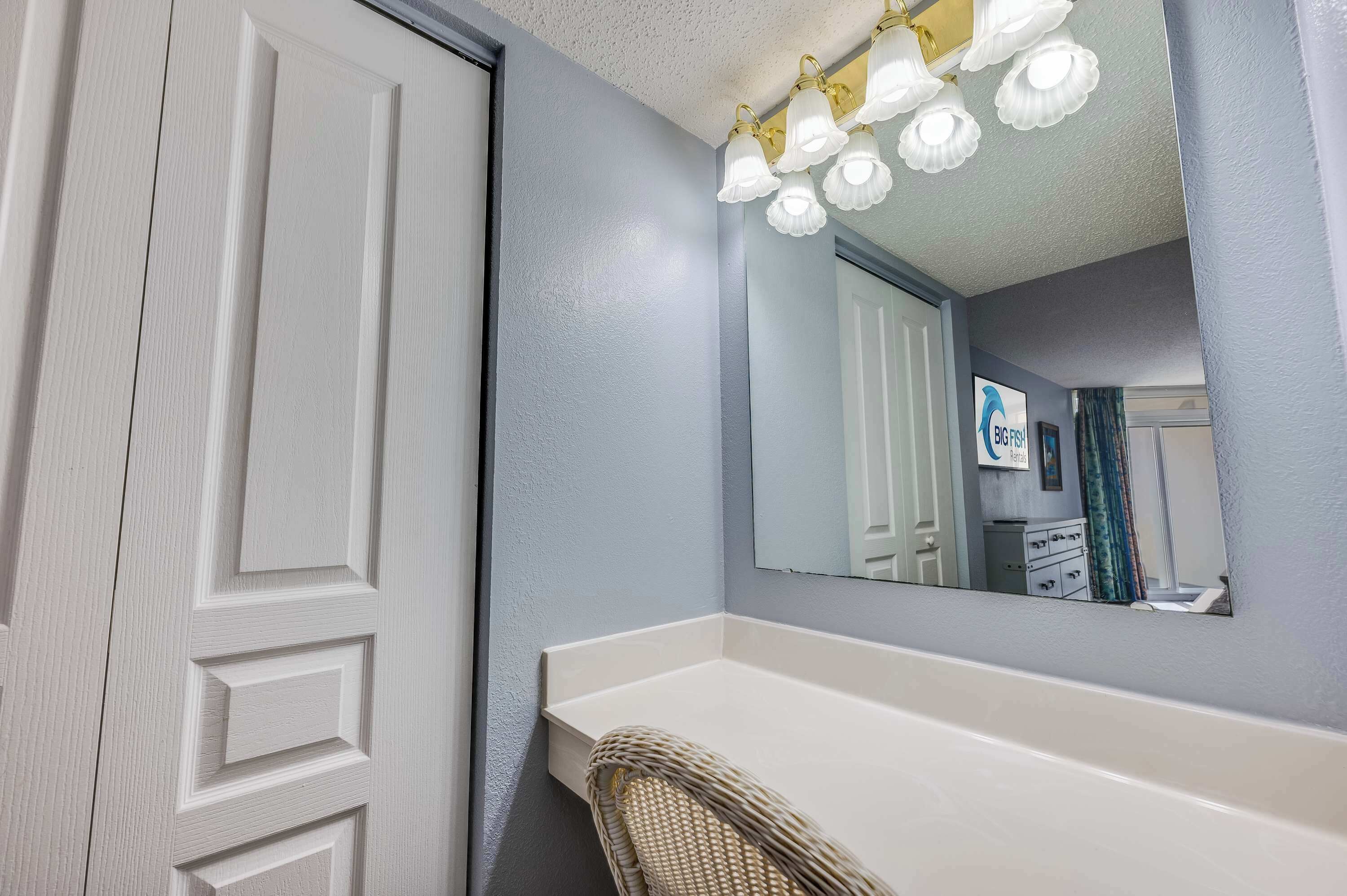 Une salle de bain avec un meuble-lavabo blanc, un grand miroir et un luminaire fixé au plafond.