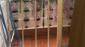 Een balkon met een witte reling, plantenbakken en uitzicht op de straat daaronder.