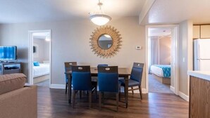 A modern living room with a dining area, a TV, and a large mirror on the wall.