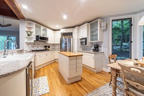 Una cocina moderna con armarios blancos, un refrigerador de acero inoxidable y una encimera de madera.