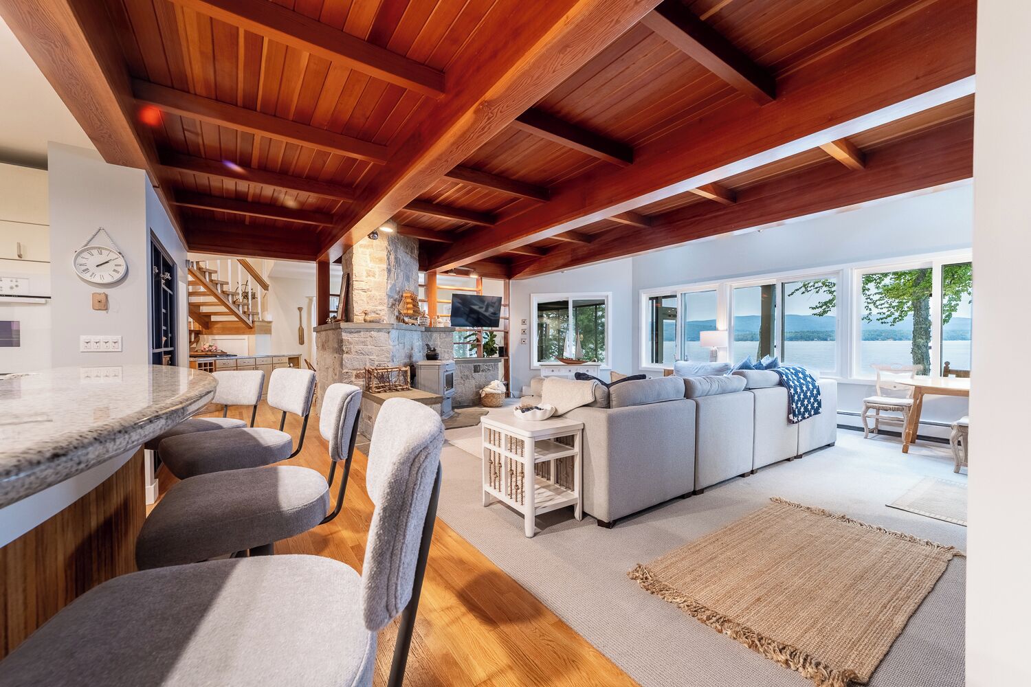 A spacious living area with a large sofa, a dining table, and a kitchen area with a stone fireplace.