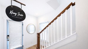 Una escalera con barandillas de madera y un cartel negro colgado del techo.