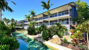 Ein Hotel mit Schwimmbad, umgeben von tropischen Pflanzen und Palmen.