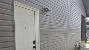 A building with a white door and a small step leading to the entrance. - Oshmild Suites, 5 mins to various shops and Cinema (Saskatoon)