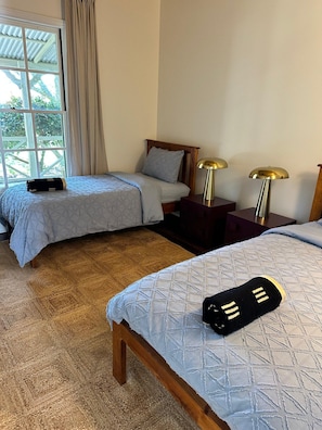 Una camera d'albergo con due letti, un'ampia finestra con tende e due abat-jour.