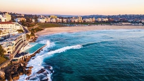 A coastal town with a beach, a rocky shoreline, and buildings along the coast. - BGs at famous Bondi Beach (North Bondi)