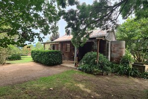 A rustic wooden building with a porch, surrounded by lush greenery and a well-maintained garden. - Architectural Cottage in heart of Kangaroo Valley (Barrengarry)