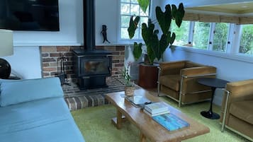 A cozy living room with a fireplace, comfortable seating, and a large window.