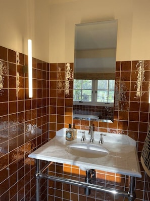 A bathroom with a large mirror, a sink with two faucets, and a window above the sink. - Architectural Cottage in heart of Kangaroo Valley (Barrengarry)