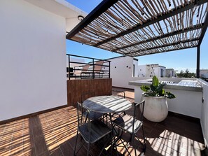 A rooftop terrace with a wooden pergola, a round table with chairs, and a potted plant. - New 3BR PH Jacuzzi, Views, GYM, Pool, Cinema, WiFi (Tulum)
