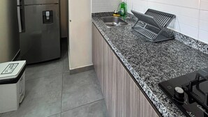 A kitchen with a stainless steel refrigerator, a microwave, a sink, and a stove. - ApartaHotel Retiro 79 (Bogotá)