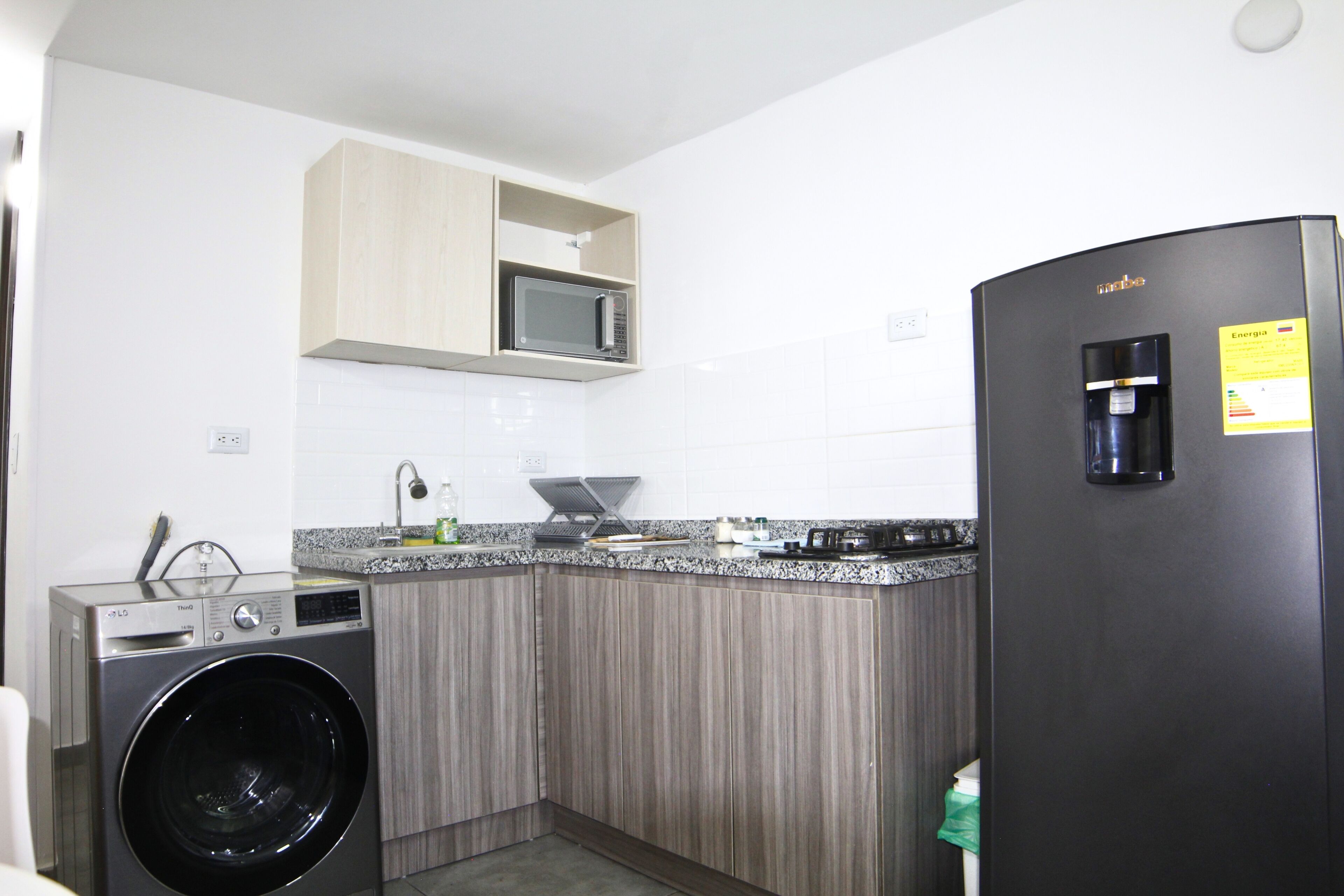 Uma cozinha compacta com máquina de lavar, micro-ondas e frigorífico.