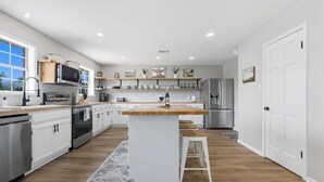 A modern kitchen with white cabinets, a wooden island, and stainless steel appliances. - Rivers Oaks-the Ranch House Pool & Hot-tub! (Fredericksburg)