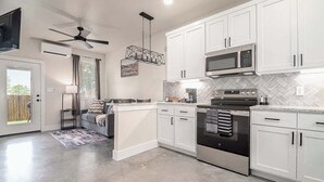 A modern kitchen with white cabinets, a stainless steel oven, and a microwave. - Pet Friendly W/hot-tub-six Minutes to Downtown! (Fredericksburg)