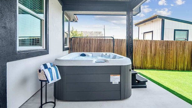 A hot tub in a covered outdoor area with a wooden fence and a grassy lawn in the background. - Pet Friendly W/hot-tub-six Minutes to Downtown! (Fredericksburg)