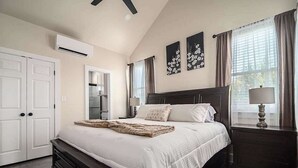 A bedroom with a large bed, a nightstand, a dresser, and a window with curtains. - Pet Friendly W/hot-tub-six Minutes to Downtown! (Fredericksburg)