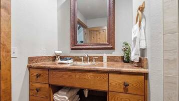 A bathroom with a wooden vanity, a mirror, a sink, and a towel rack.