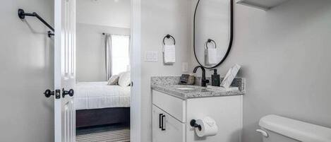 A modern bathroom with a toilet, sink, and mirror.