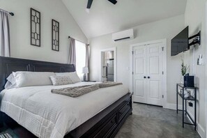 Une chambre à coucher avec un grand lit, un téléviseur fixé au mur et une armoire.