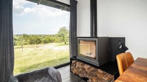 Una habitación acogedora con chimenea de piedra, un sillón cómodo y una mesa de comedor.