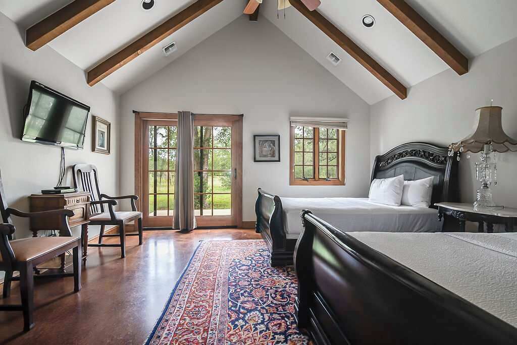Un dormitorio con una cama grande, un escritorio, una silla, un televisor y una ventana con vistas a zonas verdes.