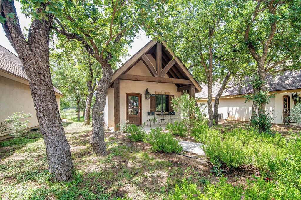 A rustic cabin with a pitched roof, surrounded by mature trees and a well-maintained garden.