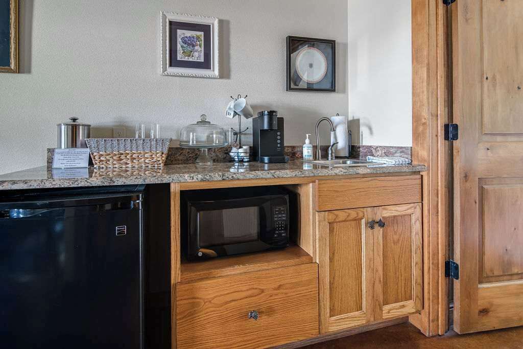 Une cuisine compacte équipée d’un four à micro-ondes encastré, d’une machine à café et d’un égouttoir à vaisselle.