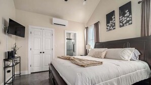 A bedroom with a bed, a TV, a desk, and a wardrobe. - Live Oak Cabins-sleeps 8 W/hot-tubs (Fredericksburg)