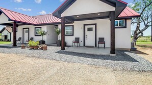 A modern two-story house with a covered patio area, a gravel driveway, and outdoor seating. - Live Oak Cabins-sleeps 8 W/hot-tubs (Fredericksburg)