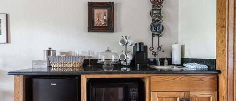 Una cocina compacta con un refrigerador negro, un microondas y un mueble de madera.