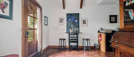Une pièce spacieuse avec une porte en bois, une table à manger avec des tabourets, une cheminée et une bibliothèque.
