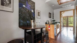 Eine moderne Küche mit einem Holztisch, Barhocker und einem großen Gemälde einer blauen Blume.