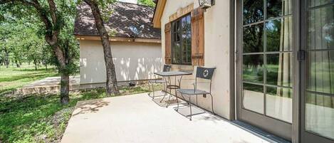 A patio with a table and chairs, a large sliding glass door, and a small outdoor light fixture.