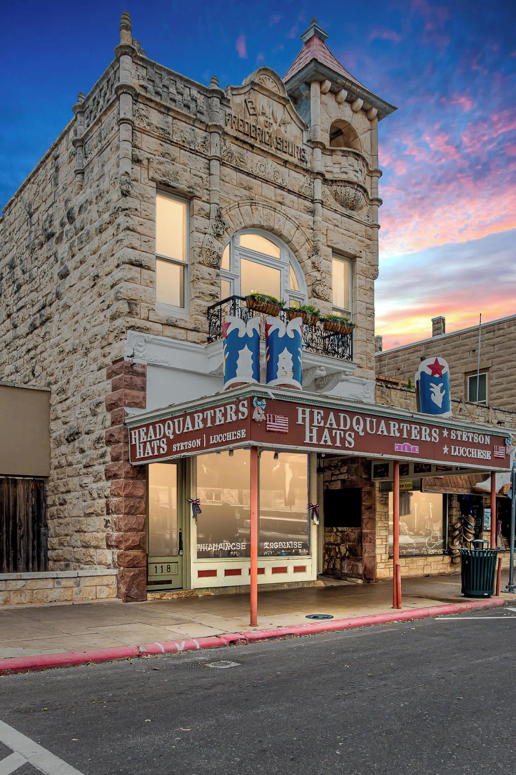 A historic building with a stone facade, a marquee sign for 'Headquarters Hats' and 'Stetson & Lucchese', and a small tower with a balcony.