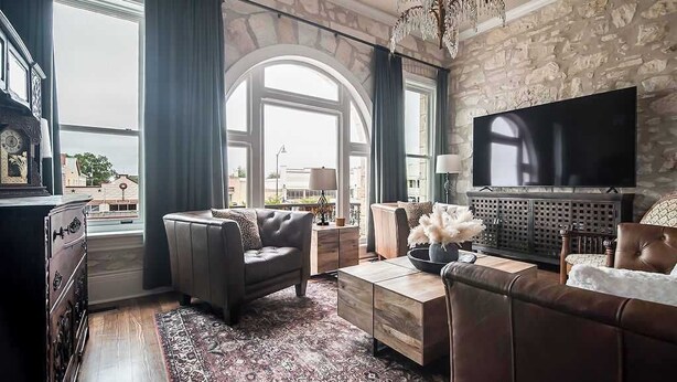 Ein Wohnzimmer mit einer Steinwand, einem großen Fernseher, Ledersofas und einem gemusterten Teppich.