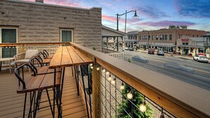 Eine Holzterrasse mit Sitzgelegenheiten im Freien mit Blick auf eine Straße mit Gebäuden und Autos.