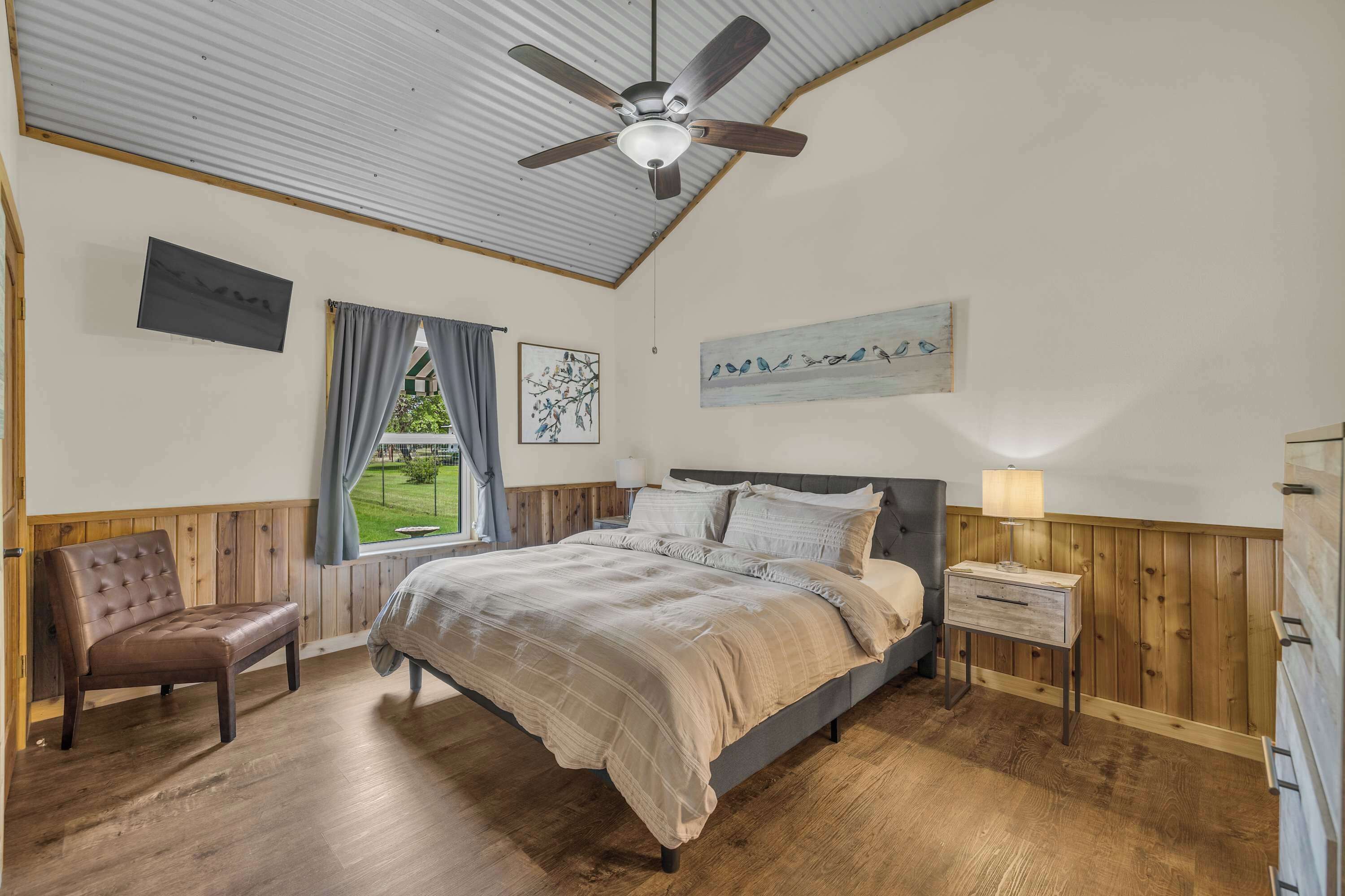 A bedroom with a bed, a wooden bench, a nightstand, and a ceiling fan.