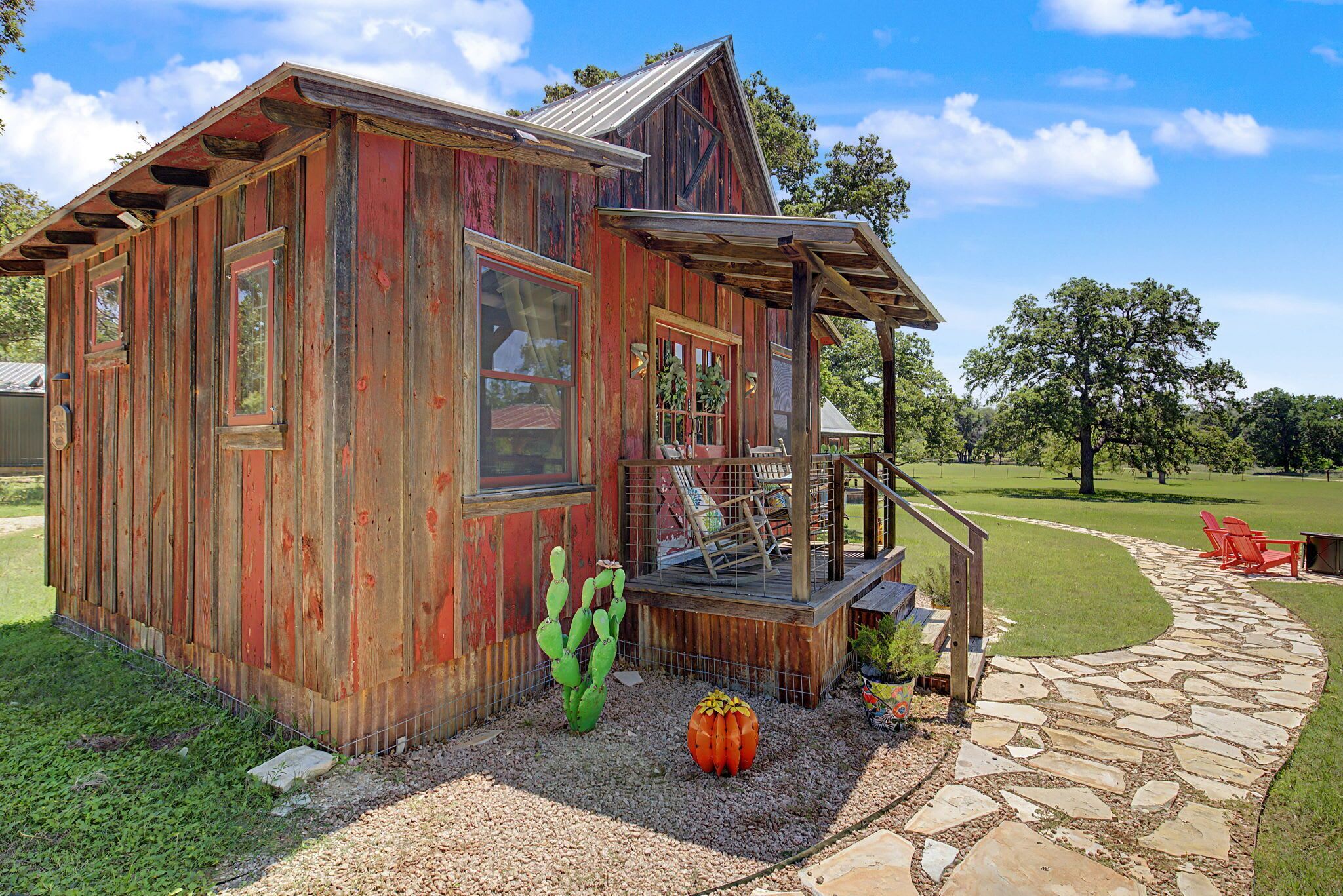 Een houten blokhut in landelijke stijl met een veranda, een cactus en een pompoen decoratie.