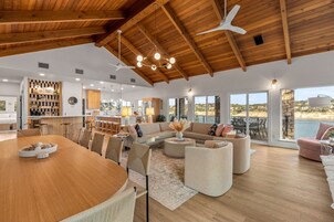 Uma sala de estar espaçosa com teto de madeira, uma grande mesa de jantar e um agradável espaço para sentar.