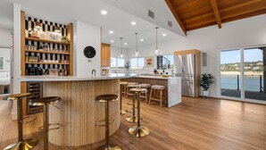 Una cocina moderna con una isla central, taburetes de bar y vista al mar.