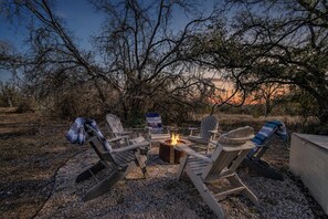 An outdoor seating area with Adirondack chairs around a fire pit. - Hye Life in the Hill Country! (Johnson City)