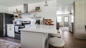 A modern kitchen with a central island, built-in appliances, and a brick accent wall. - Suniland W/pool, Hot-tub and Sauna! (Fredericksburg)
